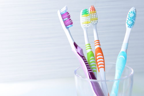 A group of colorful toothbrushes in a clear glass.