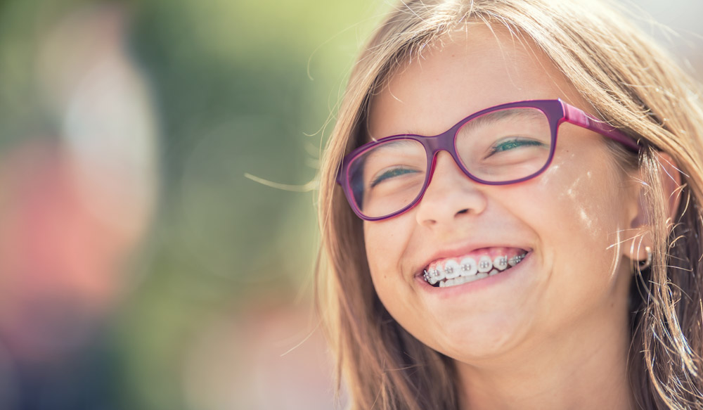 Young girl with braces, following proper Utah pediatric dentistry guidelines.