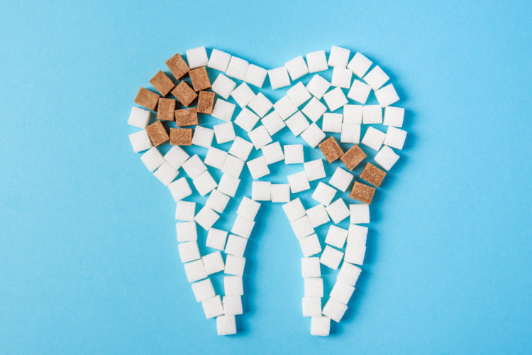 Pediatric dentist visual aid of sugar cubes arranged to depict a tooth with cavities