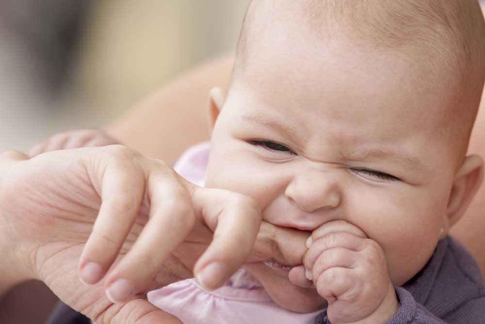 Image of baby biting finger while teething. Pediatric dentistry concept.