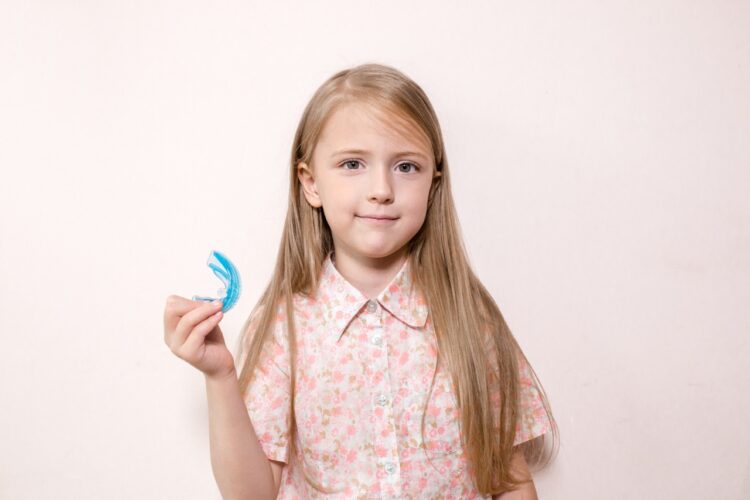 little girl holds a mouth guard for bruxism